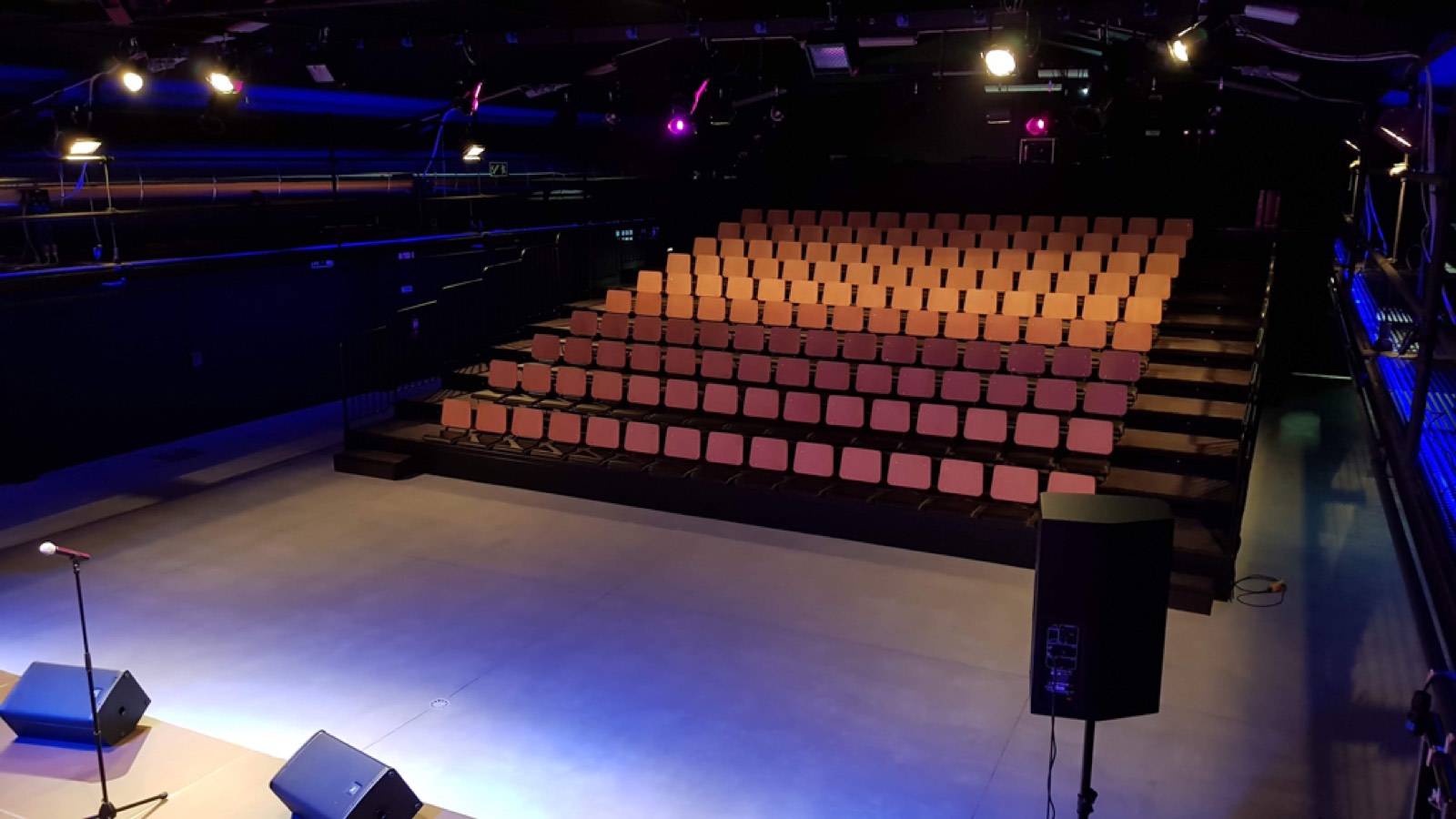 A sala da Fábrica da Criatividade antes do espetáculo, com a plateia vazia e as luzes de palco acesas.